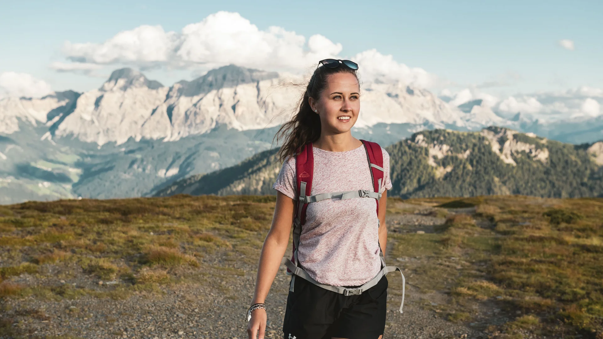 Wanderin mit Rucksack vor einer alpinen Bergkulisse