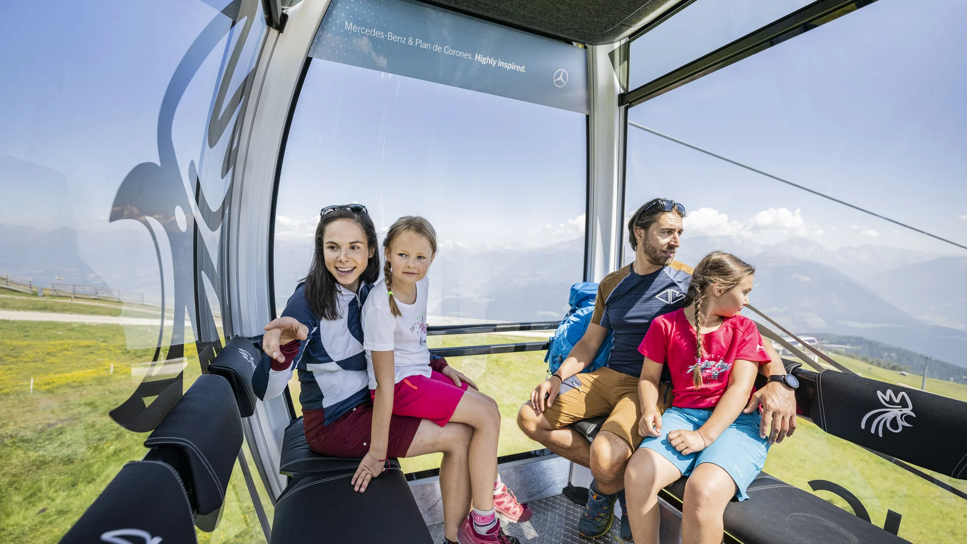 Familie fährt in einer Seilbahnkabine mit Blick auf die Berglandschaft