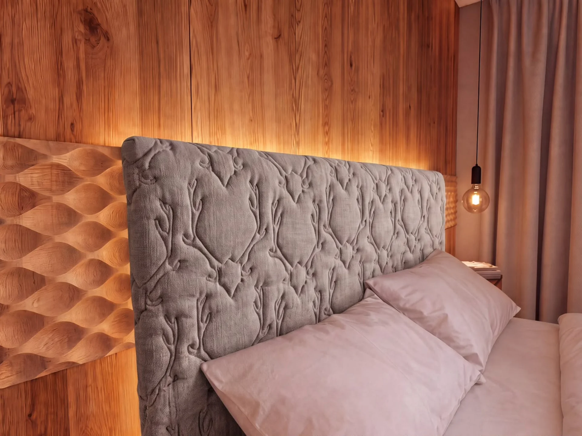 Ihr Chalet in den Dolomiten mit privater Sauna Bett mit gepolstertem Kopfteil vor einer warm beleuchteten Holzwand