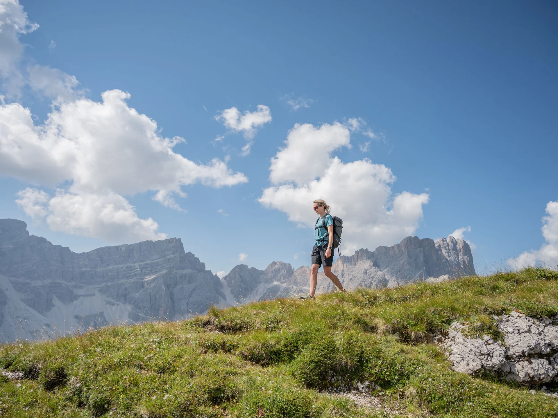 Naturparks Fanes-Sennes-Prags und Puez-Geisler | Chalet Löm Wanderin mit Rucksack auf einem Bergpfad vor einer felsigen Bergkulisse