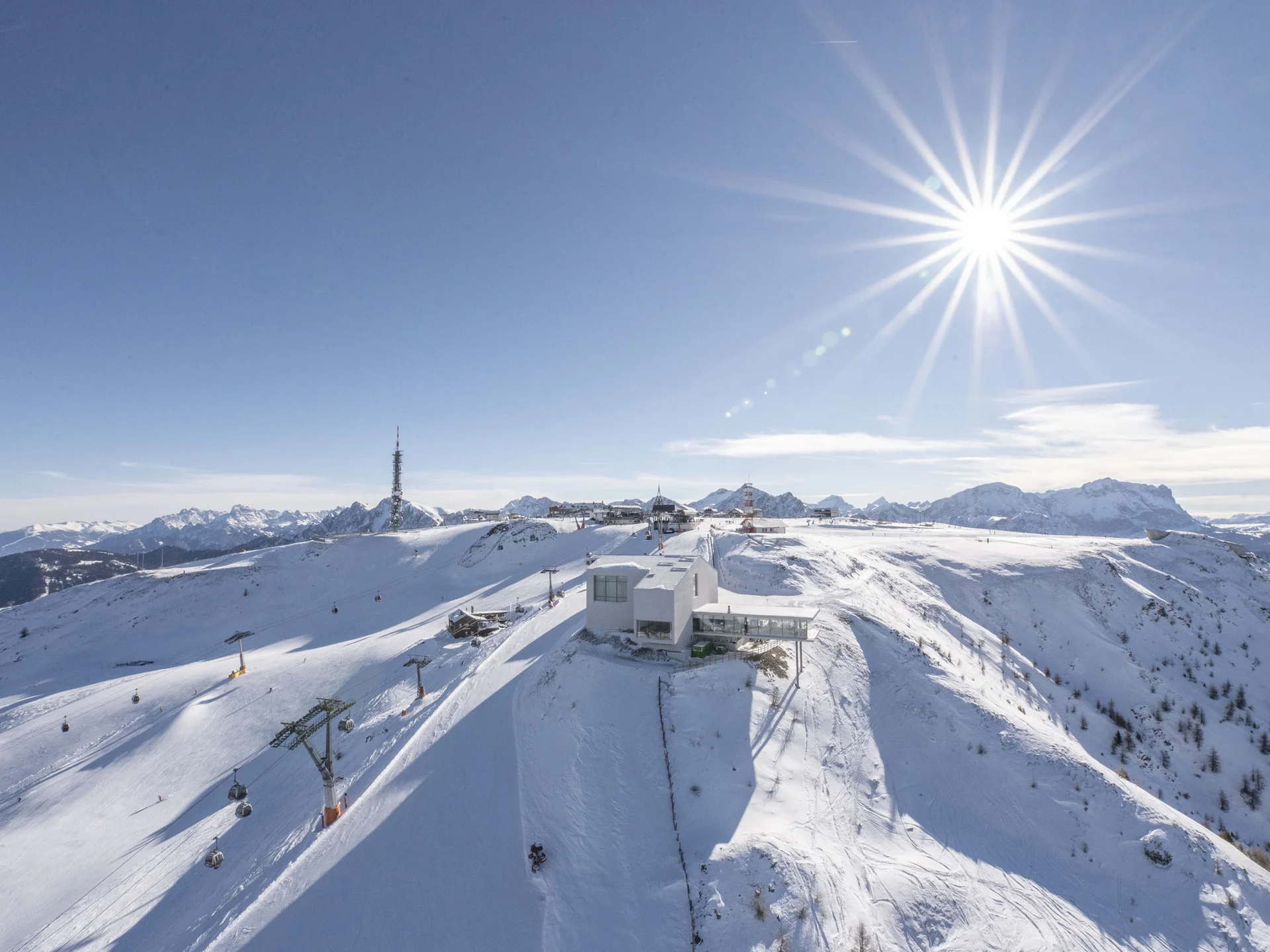 Naturparks Fanes-Sennes-Prags und Puez-Geisler | Chalet Löm Verschneiter Berggipfel mit Skiliften und Bergstation unter strahlender Sonne
