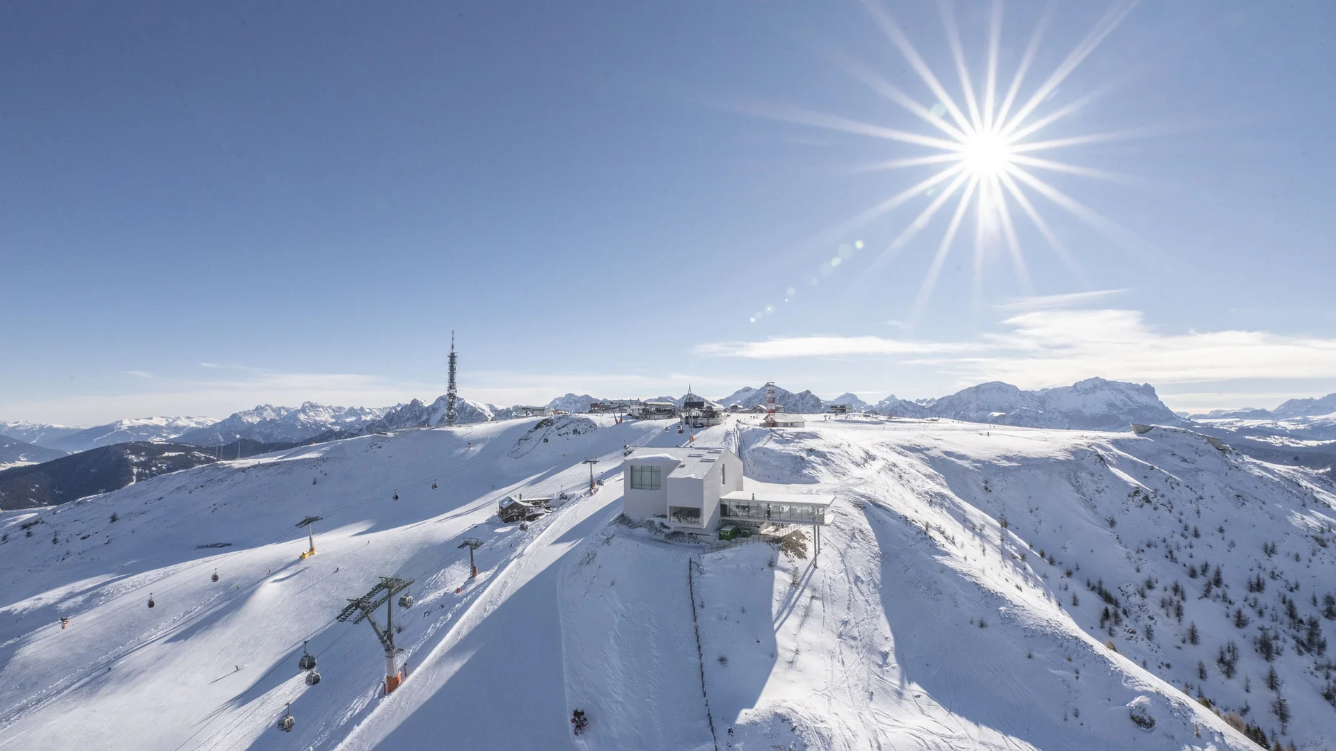 Verschneiter Berggipfel mit Skiliften und Bergstation unter strahlender Sonne
