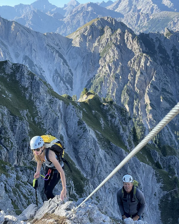 Naturparks Fanes-Sennes-Prags und Puez-Geisler | Chalet Löm Zwei Bergsteiger mit Helmen klettern an einem Seil über einen steilen Felsgrat