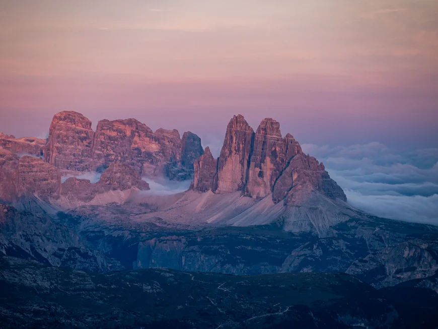Beleuchtete Berggipfel ragen bei Sonnenuntergang über ein Wolkenmeer