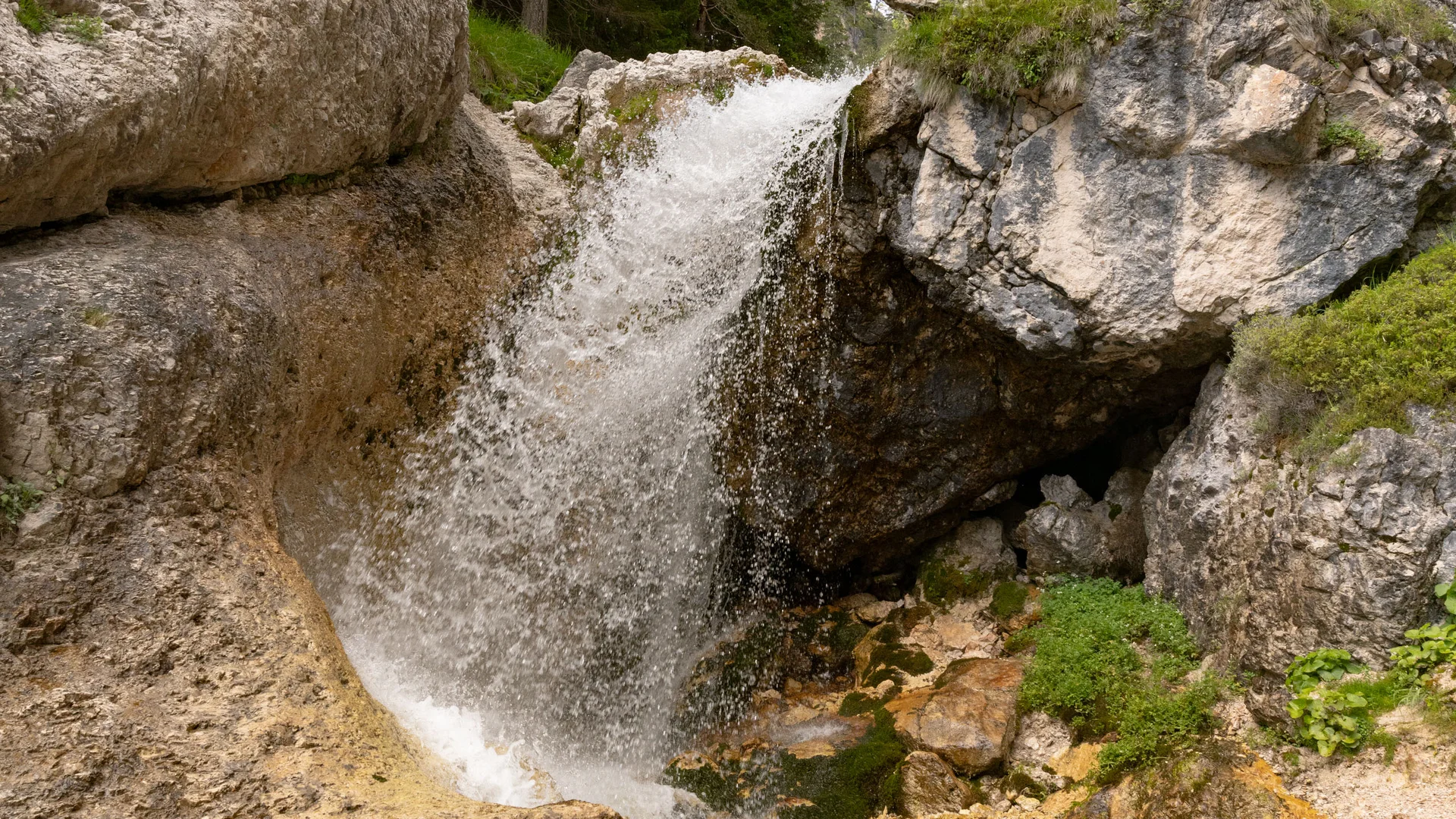 Ein Wasserfall stürzt zwischen Felsen in einem bewaldeten Gebirge hinab