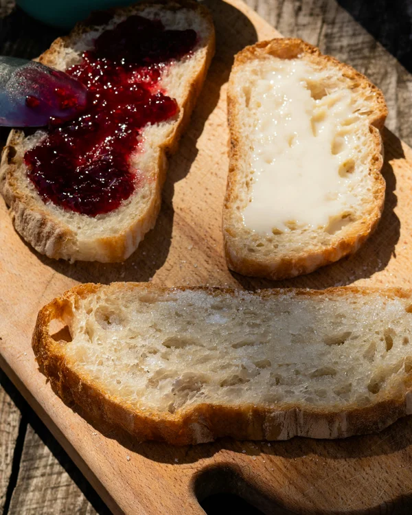 Ihr Chalet in den Dolomiten mit privater Sauna Brotscheiben mit roter Marmelade und hellem Aufstrich auf einem Holzbrett