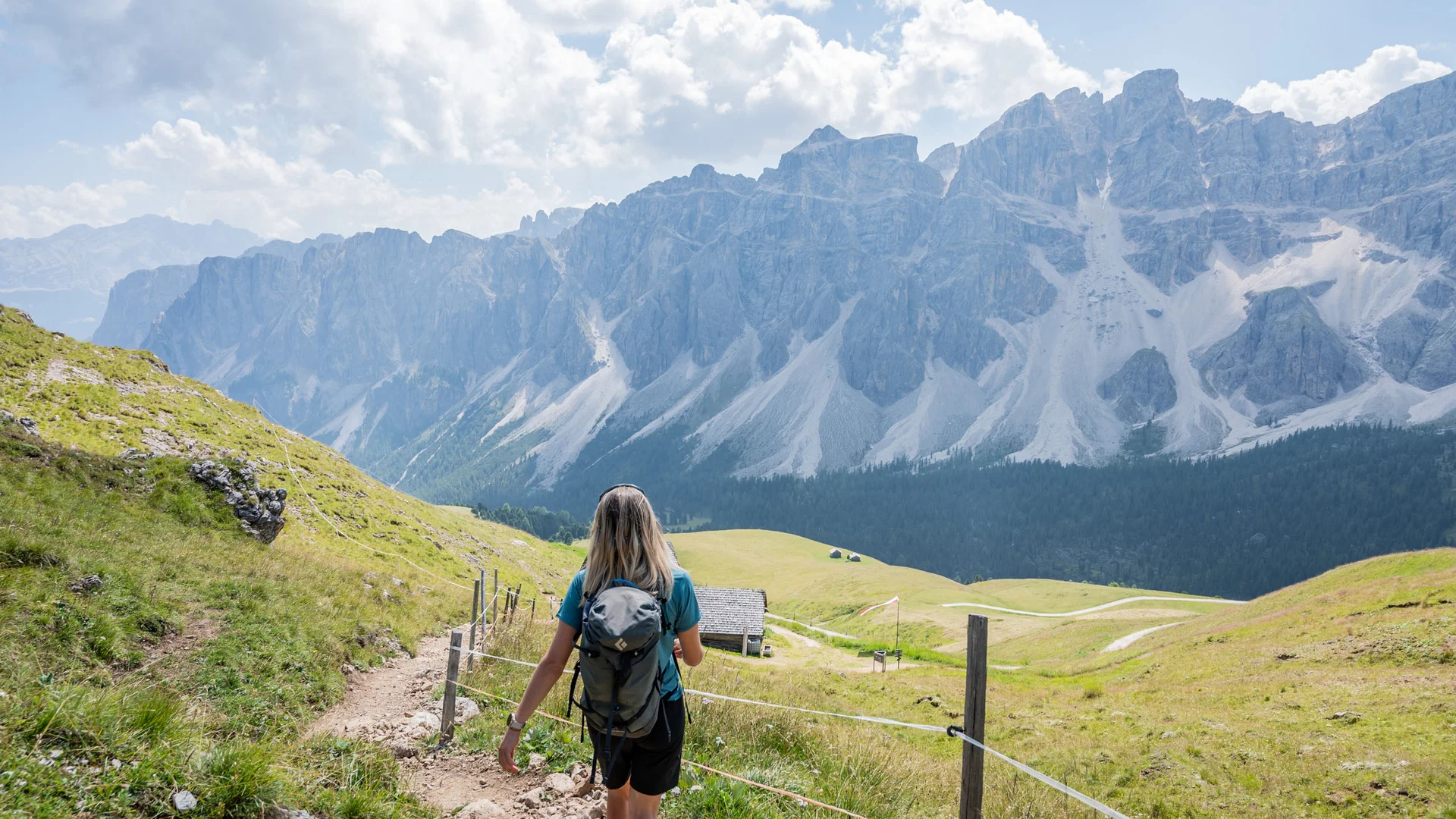 Wanderin auf einem Bergpfad mit Blick auf eine imposante Bergkette
