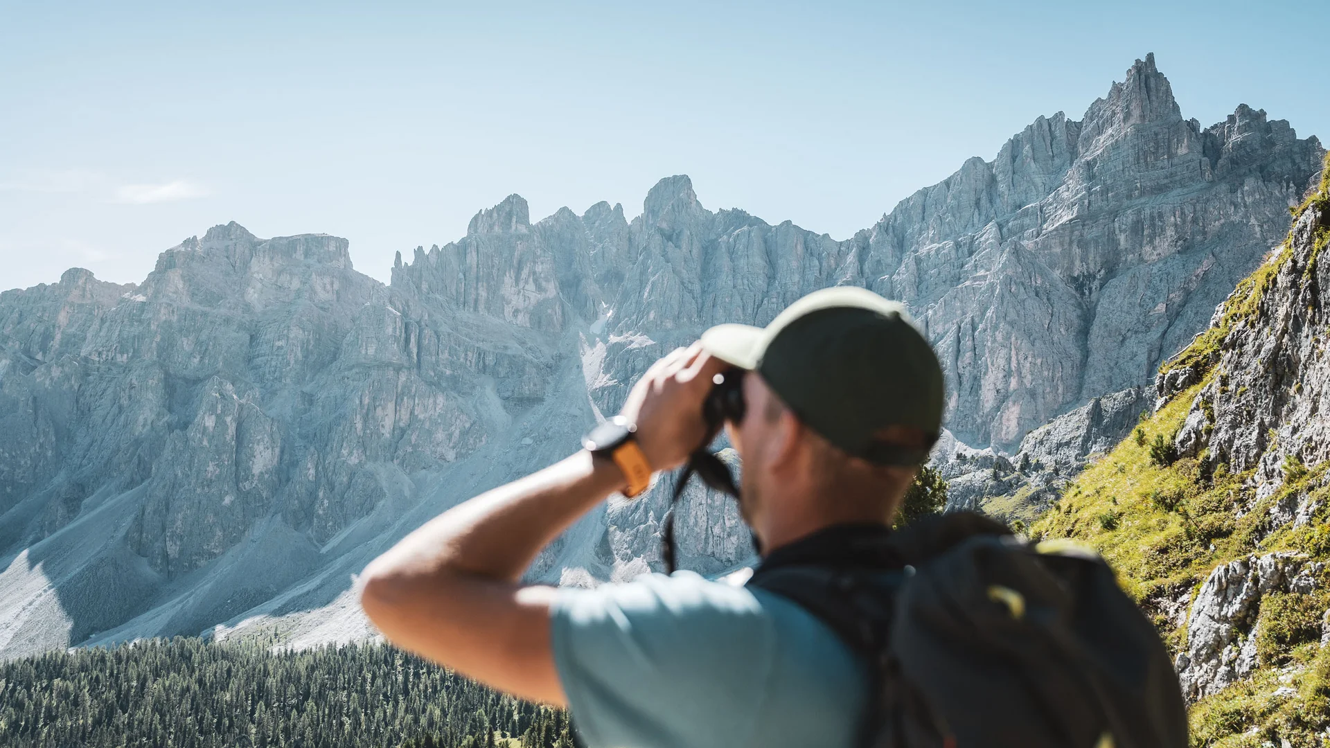 Naturparks Fanes-Sennes-Prags und Puez-Geisler | Chalet Löm Wanderer blickt mit einem Fernglas auf eine zerklüftete Bergkette