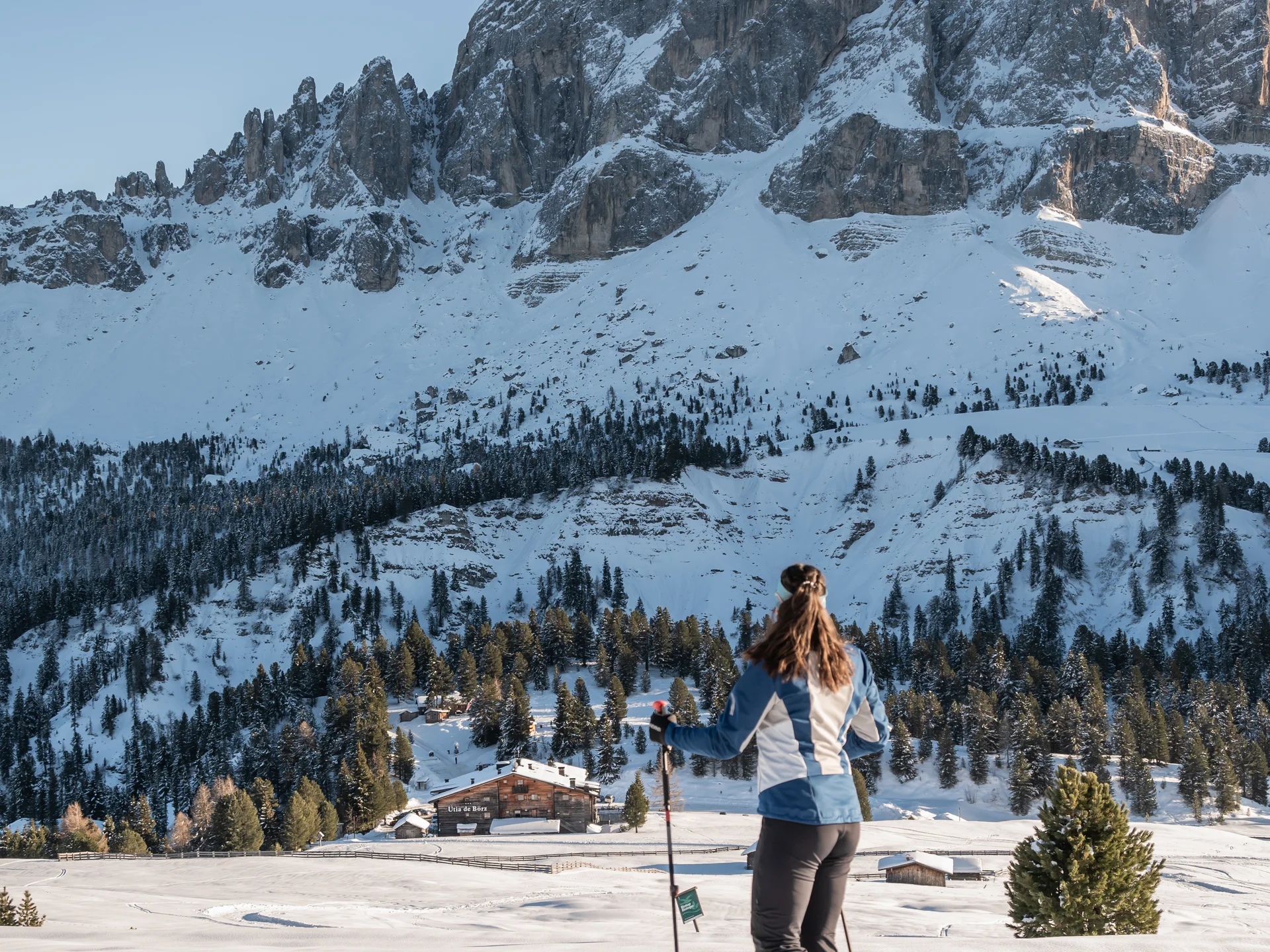 Naturparks Fanes-Sennes-Prags und Puez-Geisler | Chalet Löm Frau mit Stöcken auf Schneeschuhen vor einer verschneiten Bergkulisse