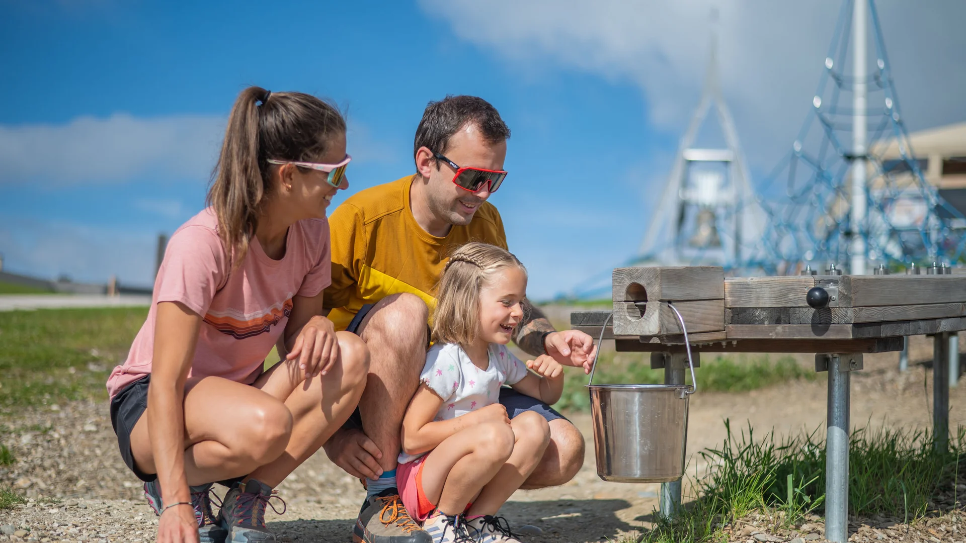 Familie an einer Holz-Wasserstation mit Eimer im Freien