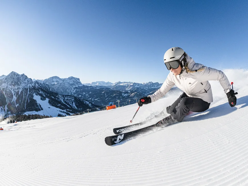 Naturparks Fanes-Sennes-Prags und Puez-Geisler | Chalet Löm Skifahrer fährt eine verschneite Piste vor einer Bergkulisse hinunter